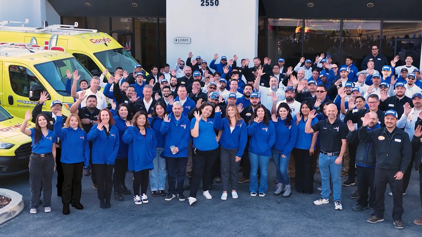 The Conejo Services team waving in front of their office and service van