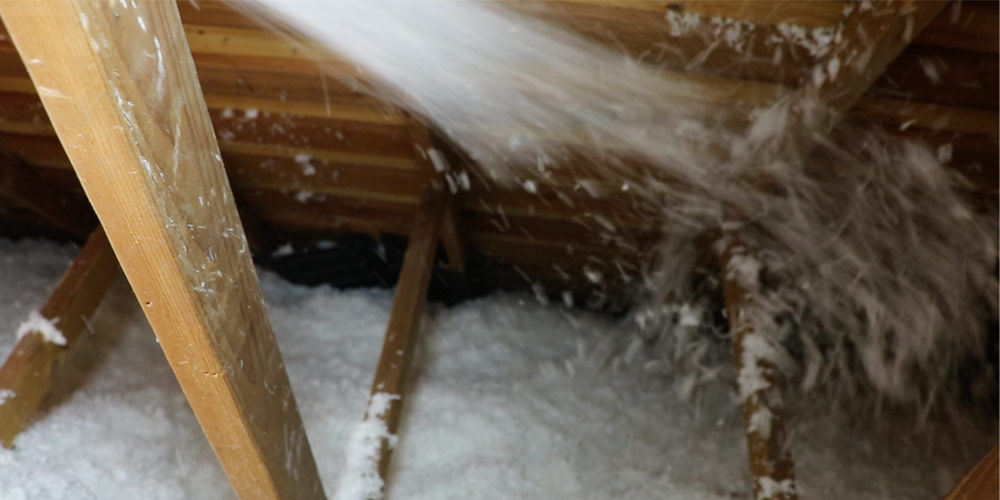 Loose-fill cellulose insulation being blown into an attic.