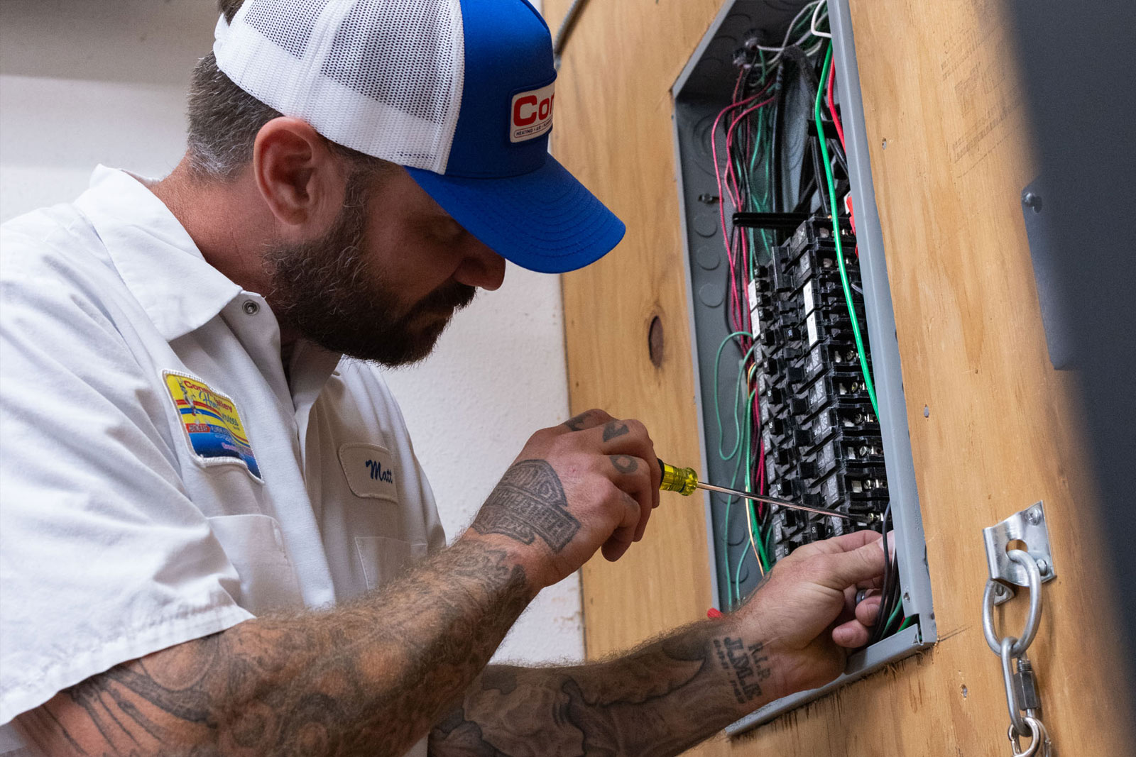 Electrician working on electrical panel, tightening screws