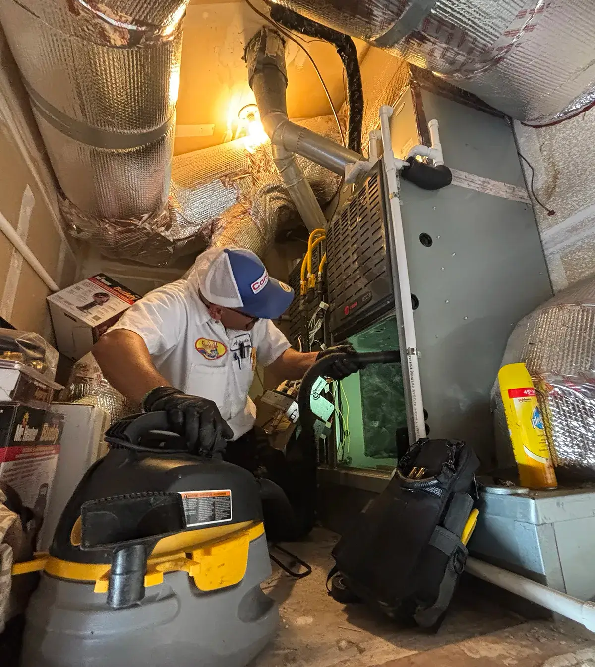 Conejo Services HVAC service technician cleaning a furnace in an attic